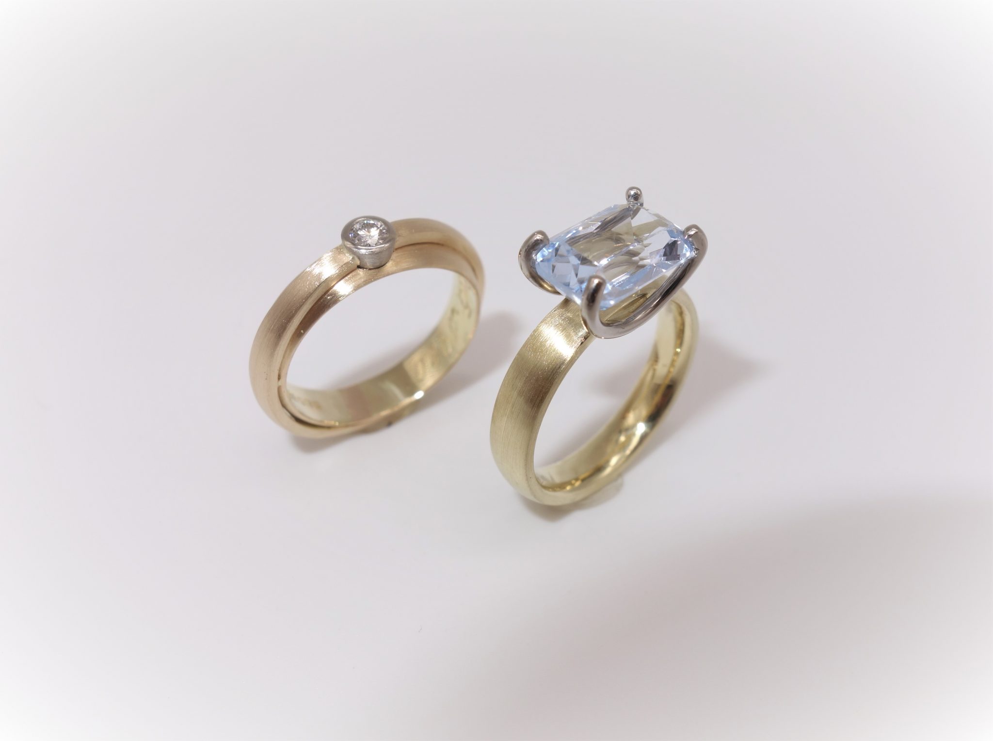 Foto von zwei gelbgoldenen Ringen mit Aquamarin und Brillant in Weißgold gefasst